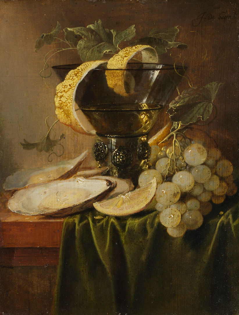 A rich display of grapes, oysters, and lemons is laid out on a table, illuminated by golden light